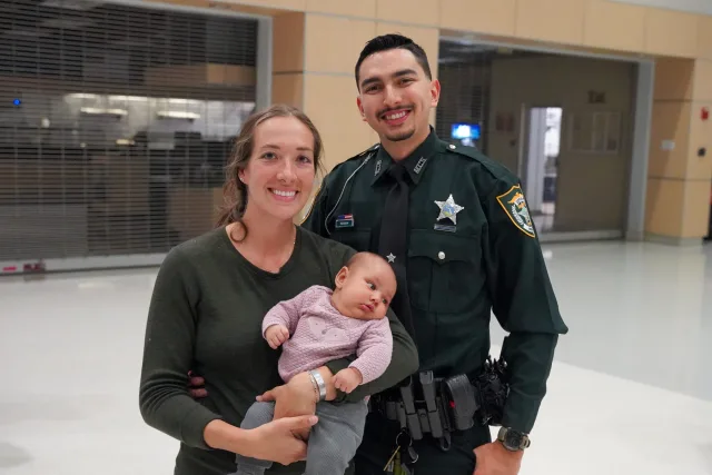 A graduate celebrating with family and a baby after the January ceremony