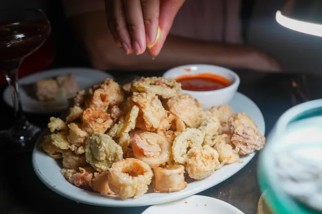 A hand squeezing lemon over calamari, photographed by Faye Constant