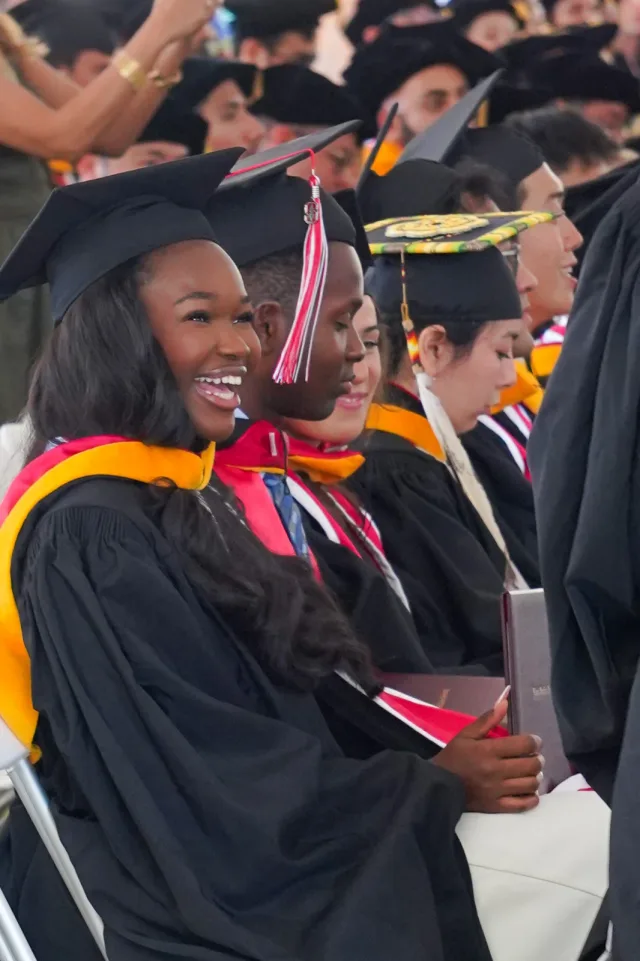 A graduate smiling with her diploma folder during the celebration