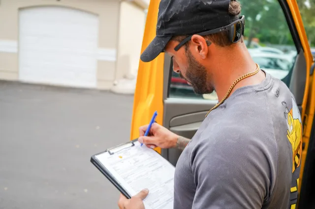 A mover reviewing a clipboard beside the truck