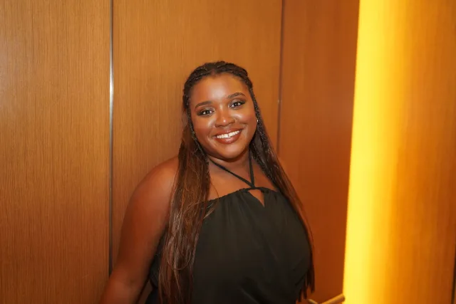 Ermeline smiling in a black dress against warm wood panels at The Westin