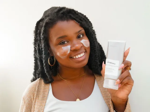 Faye smiling with cleanser on her cheeks and holding The Ordinary cleanser