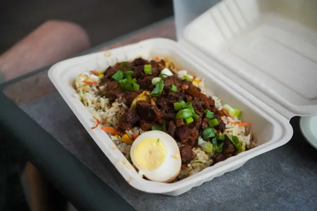 A rice bowl topped with glazed meat and chopped scallions
