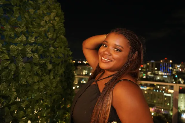 Ermeline smiling beside greenery with the city lights behind her at The Westin