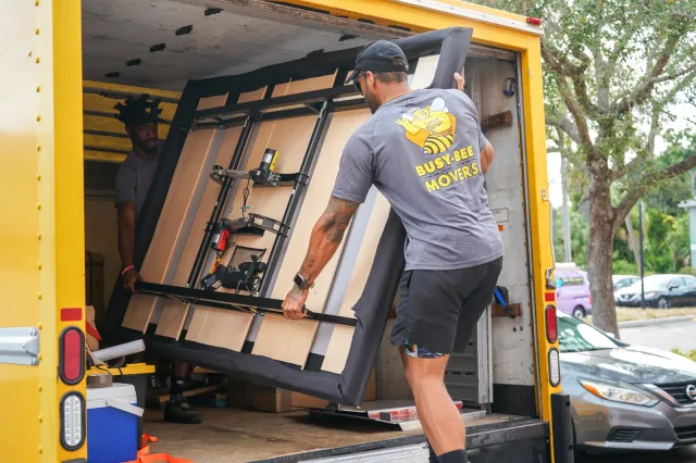 Two movers lifting a wrapped tabletop together
