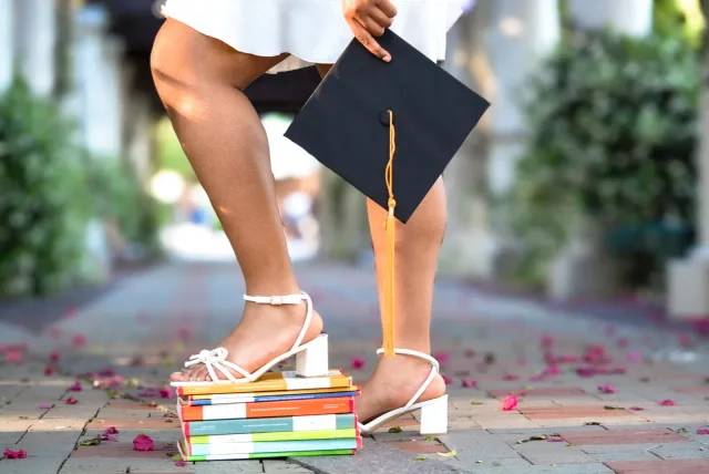 Graduation cap and heels resting on colorful books