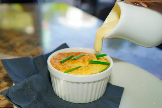 Sauce being poured over the crab soufflé at GROVE