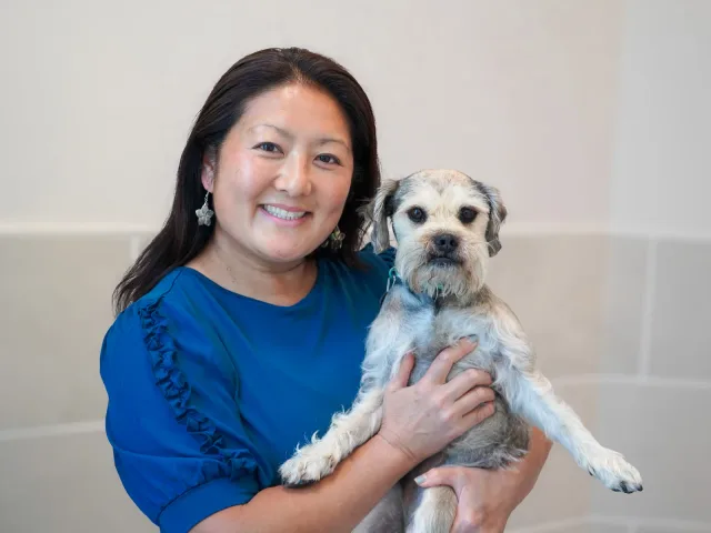 A smiling VMC team member holding a small dog