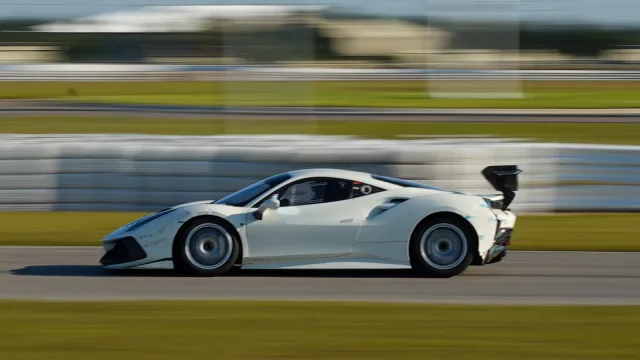 A white sports car captured in a panning shot on the circuit