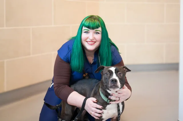 A VMC team member with green hair posing with a dog