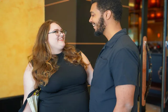 A couple smiling together against a warm yellow wall