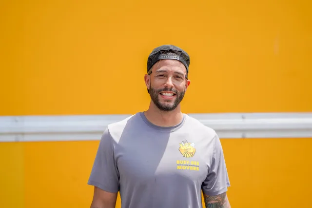 A Busy Bee team member smiling in front of the yellow moving truck