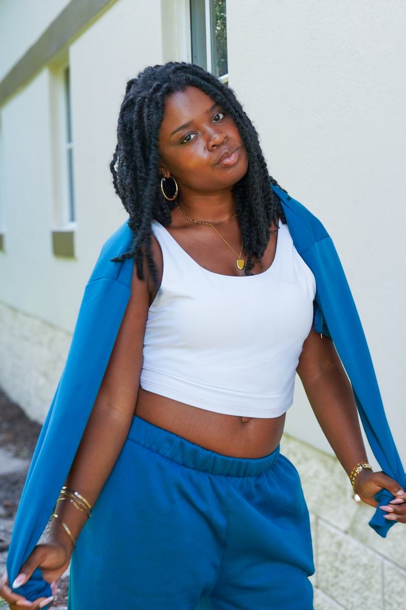 Faye Constant in a teal sweatsuit and white tank against a cream wall